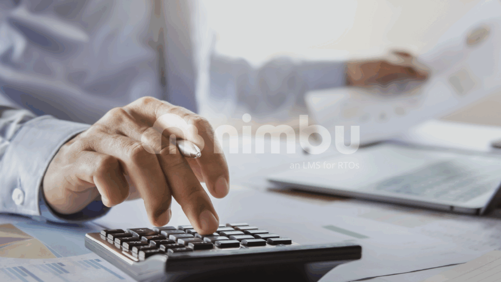 Person using a calculator and laptop to manage training costs and RTO administration