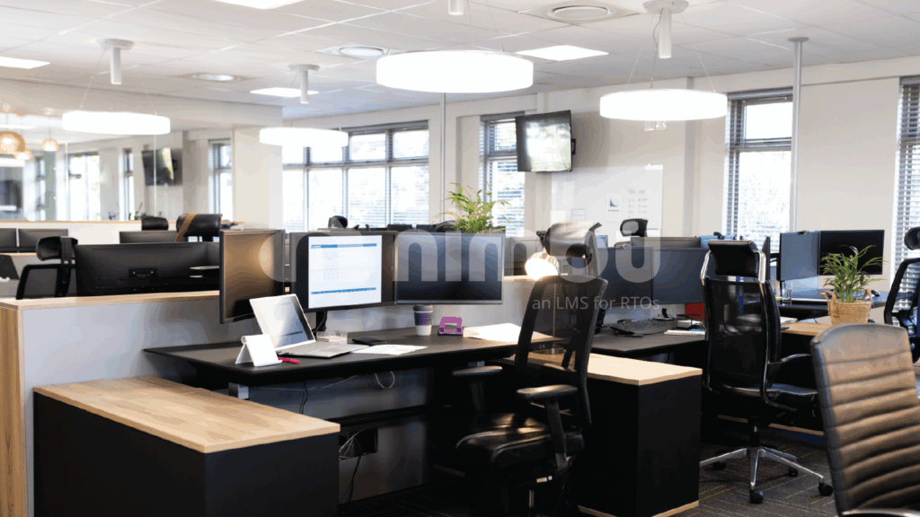 Modern open-plan office workspace with desks and computer monitors.